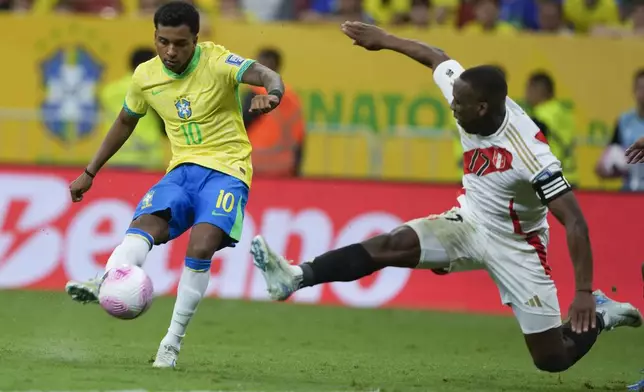 Brazil's Rodrygo, left, is challenged by Peru's Luis Advincula during a qualifying soccer match for the FIFA World Cup 2026 at Mane Garrincha Stadium in Brasilia, Brazil, Tuesday, Oct. 15, 2024. (AP Photo/Eraldo Peres)