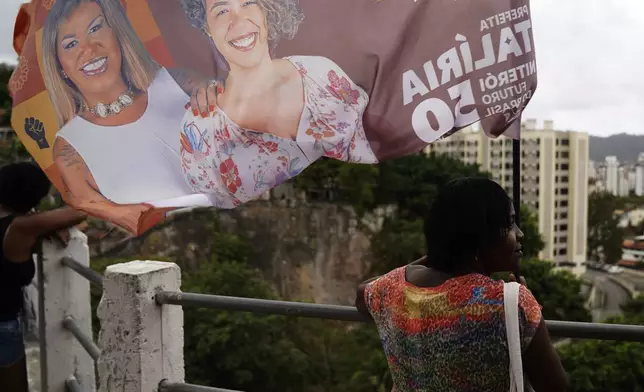 A campaign member of Benny Briolly, a transgender woman running for city council, waves a banner during a campaign event in Morro do Estado, in Niteroi, Rio de Janeiro state, Brazil, Saturday, Sept. 28, 2024. (AP Photo/Hannah-Kathryn Valles)