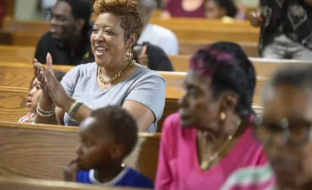 Loreasa Minor, of Turner Station, Md., seated with family friend Zoey Rogers, left, 5, claps during a service at Mt. Olive Baptist Church, Sunday, Aug. 18, 2024, in Turner Station. Turner Station is located near the former site of the Francis Scott Key Bridge, which collapsed in March. (AP Photo/Steve Ruark)