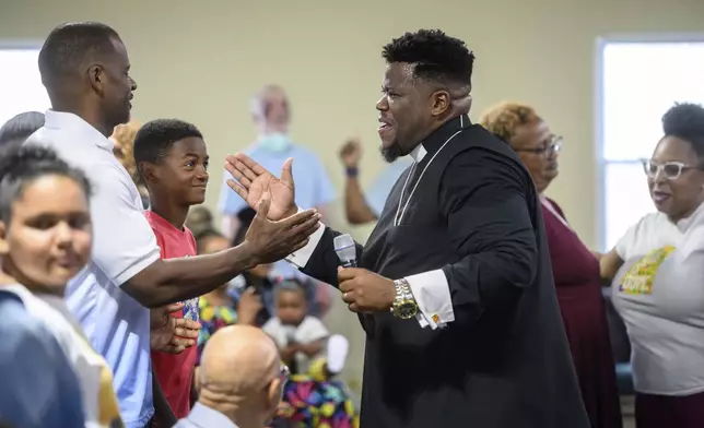 Pastor Rashad Singletary, center, greets parishioners during a service at Mt. Olive Baptist Church, Sunday, Aug. 18, 2024, in Turner Station, Md. Turner Station is located near the former site of the Francis Scott Key Bridge, which collapsed in March. (AP Photo/Steve Ruark)