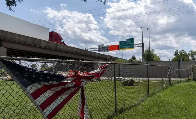 A semi truck drives past on the remaining portion of the Francis Scott Key Bridge, Tuesday, Aug. 13, 2024, as seen from the backyard of Linwood Jackon's home in Turner Station, Md. (AP Photo/Stephanie Scarbrough)