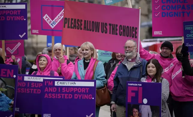 FILE - Assisted dying campaigners holds placards as they rally opposite the Houses of Parliament, as members of the House of Lords, also known as peers, are due to debate proposed legislation, in the House of Lords, in London, Friday, Oct. 22, 2021. (AP Photo/Matt Dunham, File)