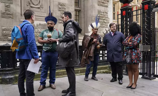 Protesters stand outside the Royal Courts of Justice in London Monday, Oct. 21, 2024, as lawyers representing around 620,000 Brazilians as well as businesses, municipal governments, members of the Krenak indigenous tribe are bringing a multibillion-pound legal action against BHP Group following the collapse of the Fundao dam in November 2015. (AP Photo/Alberto Pezzali)