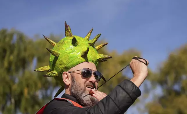 Competitor Neil Morbey wearing a conker themed hat takes part in the annual World Conker Championships at the Shuckburgh Arms in Southwick, Peterborough, England, Sunday Oct. 13, 2024. (Jacob King/PA via AP)