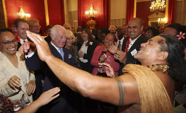 FILE - Britain's King Charles III, second from left, and Queen Camilla, third from left, smile as former Samoan rugby player Freddie Tuilagi dances during a reception to celebrate the Commonwealth Diaspora of the United Kingdom, ahead of the Commonwealth Heads of Government Meeting in Samoa, at St. James's Palace, London, on Oct. 2, 2024. (Adrian Dennis, Pool Photo via AP, File)