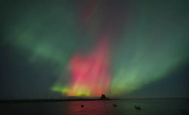 The Northern Lights, also known as the Aurora Borealis are seen over Holy Island in Northumberland, the North East coast of England, early Friday, Oct. 10, 2024. (Owen Humphreys/PA via AP)