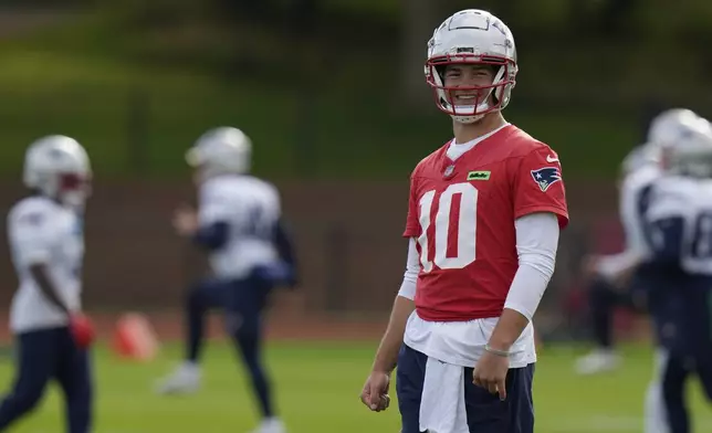 New England Patriots quarterback Drake Maye (10) smiles during NFL football practice, Friday, Oct. 18, 2024, in Harrow, England. (AP Photo/Steve Luciano)