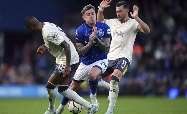 Ipswich Town's Sammie Szmodics is challenged by Everton's Ashley Young, left, and Jack Harrison, right, during the English Premier League soccer match between Ipswich Town and Everton at Portman Road, Ipswich, Saturday Oct. 19, 2024. (Bradley Collyer/PA via AP)