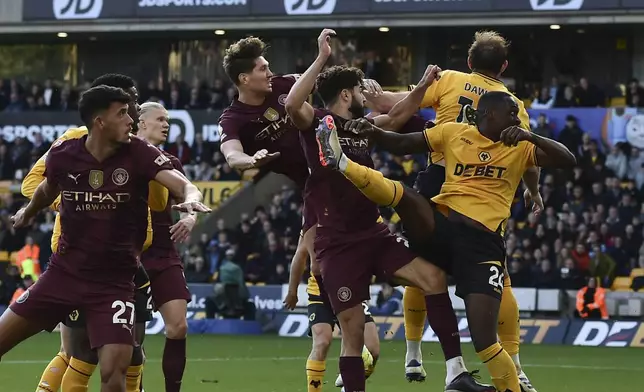 Manchester City's John Stones, top left, scores his side's 2nd goal during the English Premier League soccer match between Wolverhampton Wanderers and Manchester City at the Molineux Stadium in Wolverhampton, England, Sunday, Oct. 20, 2024. (AP Photo/Rui Vieira)