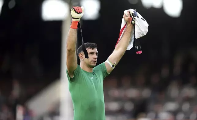 Aston Villa goalkeeper Emiliano Martinez celebrates in front of the fans after the final whistle in the English Premier League soccer match between Fulham and Aston Villa at Craven Cottage, London, Saturday Oct. 19, 2024. (John Walton/PA via AP)