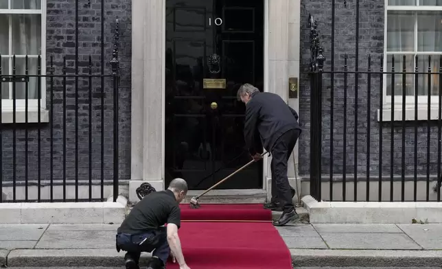 Staff members prepare the red carpet for the arrival of Ukrainian President Volodymyr Zelenskyy and NATO Secretary General Mark Rutte to 10 Downing Street in London, Thursday, Oct. 10, 2024.(AP Photo/Alastair Grant)