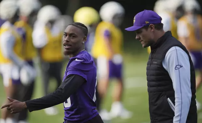 Minnesota Vikings wide receiver Justin Jefferson (18), left, talks to head coach Kevin O'Connell during a practice session at The Grove in Watford, England Friday, Oct. 4, 2024. (AP Photo/Kin Cheung)