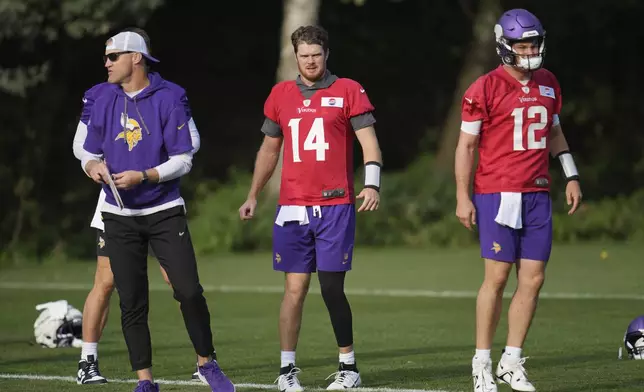 Minnesota Vikings quarterback Sam Darnold (14) and Nick Mullens (12) look on during NFL football practice at The Grove in Watford, England, Friday, Oct. 4, 2024. (AP Photo/Kin Cheung)