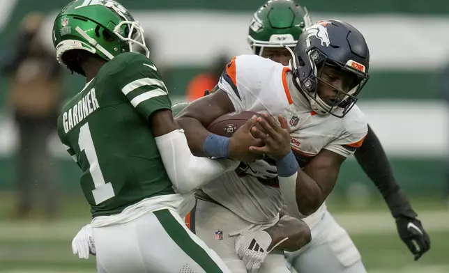 Denver Broncos running back Javonte Williams (33) is tackled by New York Jets cornerback Sauce Gardner (1), cornerback Kendall Sheffield (27) and linebacker Jamien Sherwood (44) during the third quarter of an NFL football game, Sunday, Sept. 29, 2024, in East Rutherford, N.J. (AP Photo/Seth Wenig)