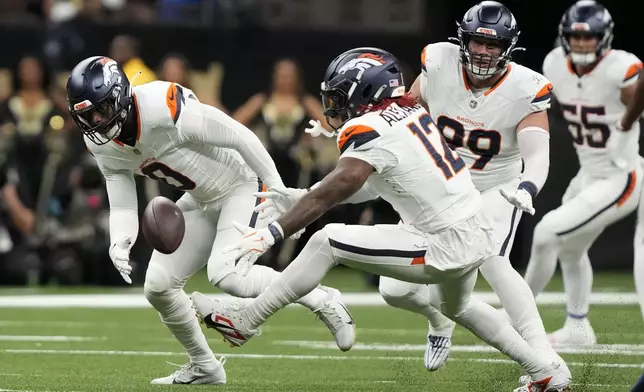 Denver Broncos linebacker Jonathon Cooper (0) and linebacker Kwon Alexander (12) look to recover a fumble during the first half of an NFL football game against the New Orleans Saints, Thursday, Oct. 17, 2024, in New Orleans. (AP Photo/Gerald Herbert)