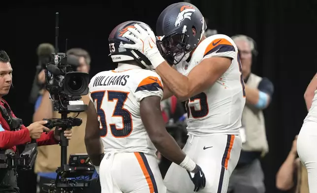 Denver Broncos running back Javonte Williams (33) celebrates with teammate tight end Lucas Krull (85) after an 8-yard touchdown run during the first half of an NFL football game against the New Orleans Saints, Thursday, Oct. 17, 2024, in New Orleans. (AP Photo/Gerald Herbert)