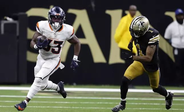 Denver Broncos running back Javonte Williams (33) runs from New Orleans Saints cornerback Alontae Taylor (1) during the second half of an NFL football game, Thursday, Oct. 17, 2024, in New Orleans. (AP Photo/Butch Dill)