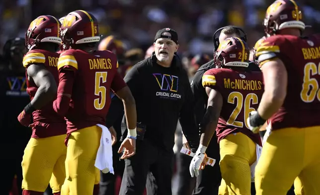 Washington Commanders head coach Dan Quinn, center, celebrates with players after a touchdown against the Cleveland Browns during the second half of an NFL football game in Landover, Md., Sunday, Oct. 6, 2024. (AP Photo/Nick Wass)