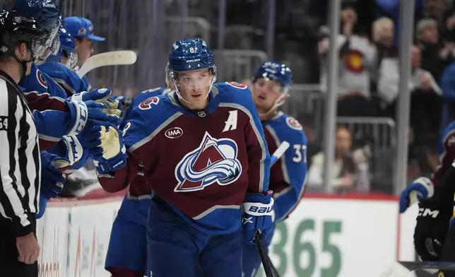 Colorado Avalanche defenseman Cale Makar is congratulated as he passes the team box after scoring a goal in the second period of an NHL hockey game against the Boston Bruins Wednesday, Oct. 16, 2024, in Denver. (AP Photo/David Zalubowski)