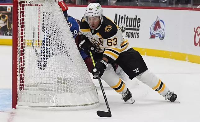 Boston Bruins left wing Brad Marchand, front, wraps around the net with the puck as Colorado Avalanche defenseman Oliver Kylington pursues in the second period of an NHL hockey game Wednesay, Oct. 16, 2024, in Denver. (AP Photo/David Zalubowski)