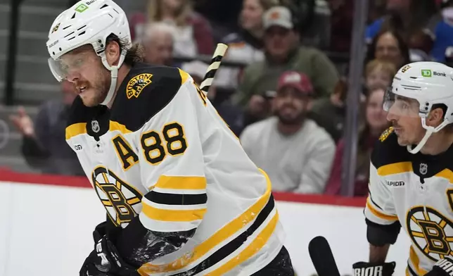 Boston Bruins right wing David Pastrnak, left, is congratulated after scoring a goal by left wing Brad Marchand in the second period of an NHL hockey game against the Colorado Avalanche Wednesday, Oct. 16, 2024, in Denver. (AP Photo/David Zalubowski)