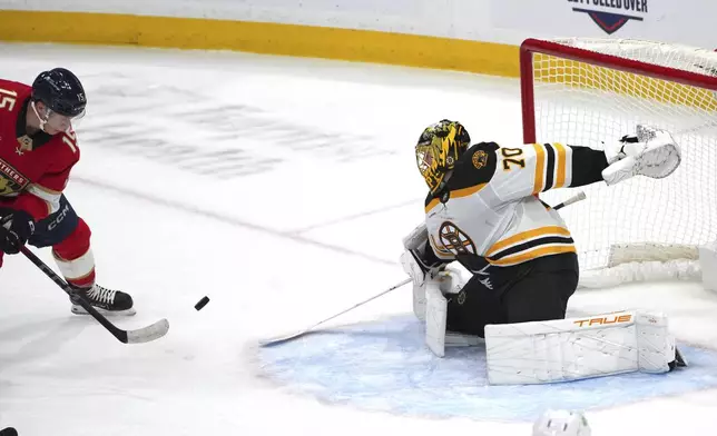 Boston Bruins goaltender Joonas Korpisalo (70) knocks the puck wide as Florida Panthers center Anton Lundell (15) closes in during the second period of an NHL hockey game, Tuesday, Oct. 8, 2024, in Sunrise, Fla. (AP Photo/Jim Rassol)