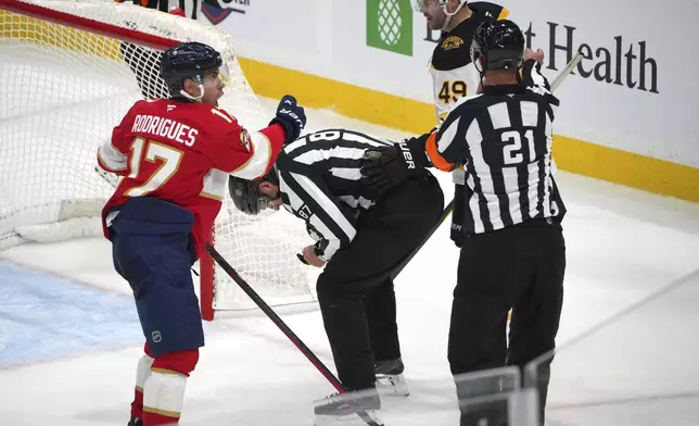 Boston Bruins left wing Max Jones (49) accidentally clips linesperson Devin Berg (87) as Florida Panthers center Evan Rodrigues (17) looks on during the second period of an NHL hockey game, Tuesday, Oct. 8, 2024, in Sunrise, Fla. (AP Photo/Jim Rassol)