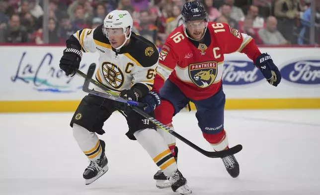 Boston Bruins left wing Brad Marchand (63) and Florida Panthers center Aleksander Barkov (16) battle for position during the first period of an NHL hockey game, Tuesday, Oct. 8, 2024, in Sunrise, Fla. (AP Photo/Jim Rassol)