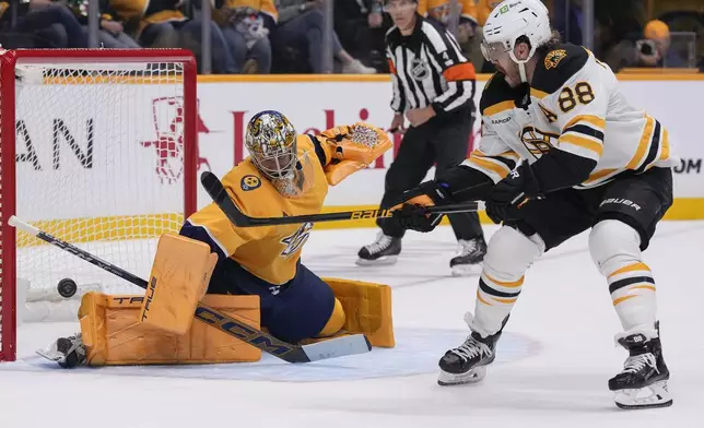 Nashville Predators goaltender Juuse Saros (74) blocks a shot on goal by Boston Bruins right wing David Pastrnak (88) during the first period of an NHL hockey game Tuesday, Oct. 22, 2024, in Nashville, Tenn. (AP Photo/George Walker IV)