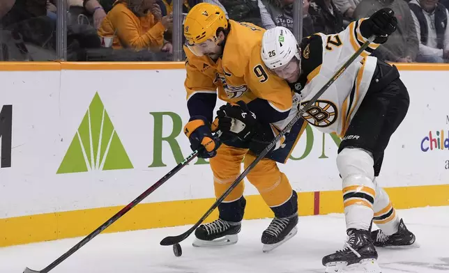 Nashville Predators left wing Filip Forsberg (9) battles Boston Bruins defenseman Brandon Carlo (25) for the puck during the second period of an NHL hockey game Tuesday, Oct. 22, 2024, in Nashville, Tenn. (AP Photo/George Walker IV)