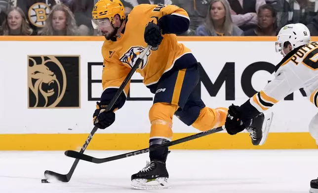 Nashville Predators defenseman Alexandre Carrier (45) shoots the puck past Boston Bruins center Matthew Poitras (51) during the second period of an NHL hockey game Tuesday, Oct. 22, 2024, in Nashville, Tenn. (AP Photo/George Walker IV)