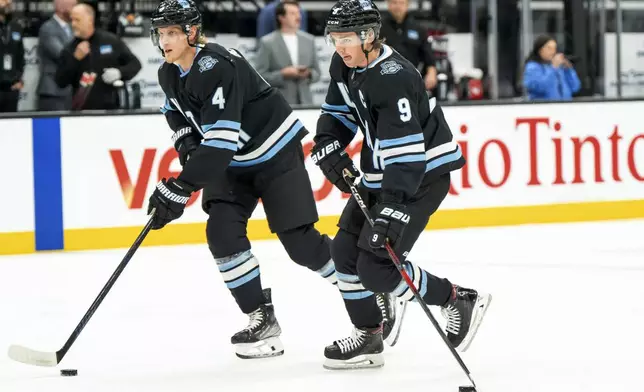 Utah Hockey Club defenseman Juuso Valimaki (4) and center Clayton Keller (9) warm up before an NHL hockey game against the Boston Bruins, Saturday, Oct. 19, 2024, in Salt Lake City. (AP Photo/Spenser Heaps)