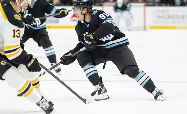 Utah Hockey Club right wing Josh Doan (91) moves the puck against Boston Bruins center Charlie Coyle (13) during the second period of an NHL hockey game, Saturday, Oct. 19, 2024, in Salt Lake City. (AP Photo/Spenser Heaps)