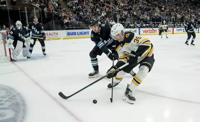 Boston Bruins center Morgan Geekie (39) tries to move the puck under pressure from Utah Hockey Club defenseman Michael Kesselring during the first period of an NHL hockey game, Saturday, Oct. 19, 2024, in Salt Lake City. (AP Photo/Spenser Heaps)