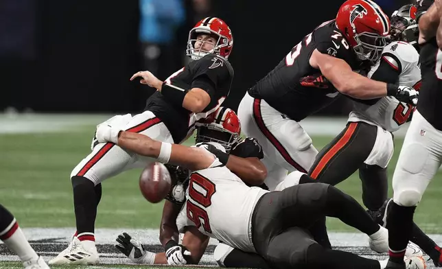 Atlanta Falcons quarterback Kirk Cousins (18) loses the football as he is sacked by Tampa Bay Buccaneers defensive end Logan Hall (90) during the first half of an NFL football game Thursday, Oct. 3, 2024, in Atlanta. (AP Photo/John Bazemore)