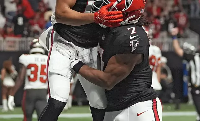 Atlanta Falcons wide receiver KhaDarel Hodge (12) celebrates with running back Bijan Robinson (7) after Hodge scored the game-wining touchdown against the Tampa Bay Buccaneers during overtime in an NFL football game Thursday, Oct. 3, 2024, in Atlanta. (AP Photo/John Bazemore)