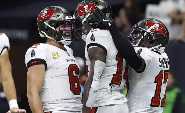 Tampa Bay Buccaneers wide receiver Chris Godwin, middle, is congratulated by quarterback Baker Mayfield (6) and wide receiver Sterling Shepard (17) after scoring against the New Orleans Saints during the first half of an NFL football game in New Orleans, Sunday, Oct. 13, 2024. (AP Photo/Butch Dill)