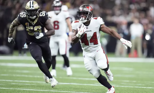 Tampa Bay Buccaneers running back Sean Tucker (44) runs in front of New Orleans Saints linebacker Demario Davis (56) during the second half of an NFL football game in New Orleans, Sunday, Oct. 13, 2024. (AP Photo/Michael Conroy)