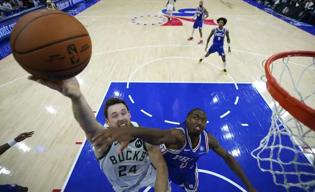 Milwaukee Bucks' Pat Connaughton, left, goes up for a shot against Philadelphia 76ers' Tyrese Maxey during the second half of an NBA basketball game, Wednesday, Oct. 23, 2024, in Philadelphia. (AP Photo/Matt Slocum)