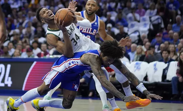 Milwaukee Bucks' Giannis Antetokounmpo, top, is fouled by Philadelphia 76ers' Kelly Oubre Jr. during the first half of an NBA basketball game, Wednesday, Oct. 23, 2024, in Philadelphia. (AP Photo/Matt Slocum)