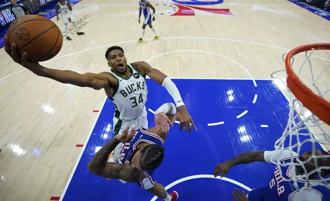 Milwaukee Bucks' Giannis Antetokounmpo, top, goes up against Philadelphia 76ers' Caleb Martin during the second half of an NBA basketball game, Wednesday, Oct. 23, 2024, in Philadelphia. (AP Photo/Matt Slocum)