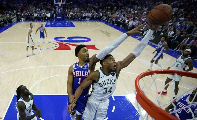 Philadelphia 76ers' KJ Martin (1) and Milwaukee Bucks' Giannis Antetokounmpo (34) reach for a rebound during the first half of an NBA basketball game, Wednesday, Oct. 23, 2024, in Philadelphia. (AP Photo/Matt Slocum)