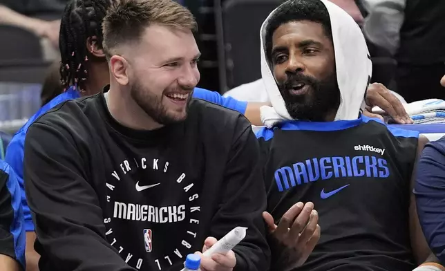Sitting on the bench Dallas Mavericks guard Luka Doncic, left, shares a laugh with teammate fellow guard Kyrie Irving during a preseason NBA basketball game against the Milwaukee Bucks Thursday, Oct. 17, 2024, in Dallas. (AP Photo/LM Otero)