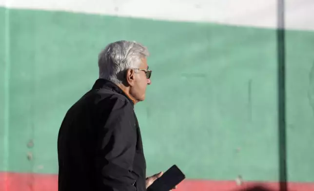 A man walks outside a polling station backdropped by Bulgarian flag in Bankya, Bulgaria, Sunday, Oct. 27, 2024. (AP Photo/Valentina Petrova)