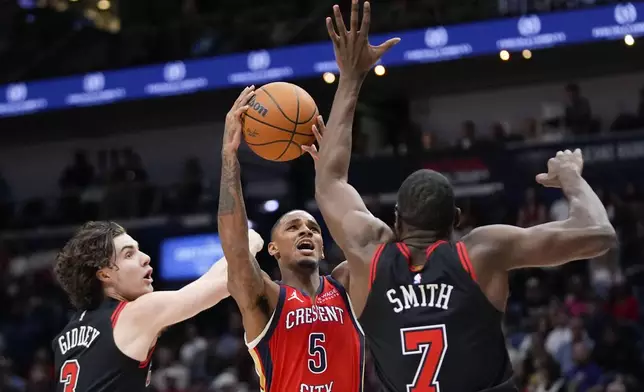 New Orleans Pelicans guard Dejounte Murray (5) goes to the basket between Chicago Bulls forward Jalen Smith (7) and guard Josh Giddey (3) in the first half of an NBA basketball game in New Orleans, Wednesday, Oct. 23, 2024. (AP Photo/Gerald Herbert)