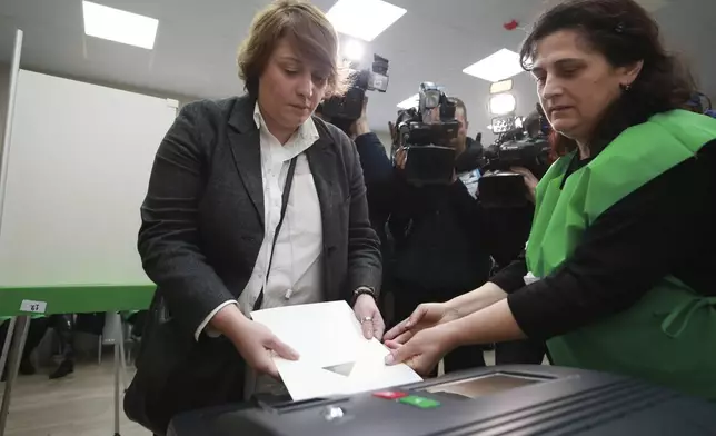 An election commission member, right, helps Elene Khoshtaria, the leader of the Strong Georgia Coalition, cast her ballot at a polling station during the parliamentary election in Tbilisi, Georgia, Saturday, Oct. 26, 2024. (AP Photo/Zurab Tsertsvadze)