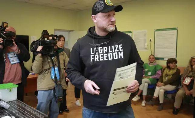 CORRECTS PARTY NAME - Zurab Japaridze, chairman of the Girchi More Freedom party, holds his ballot at a polling station during the parliamentary election in Tbilisi, Georgia, Saturday, Oct. 26, 2024. (AP Photo/Zurab Tsertsvadze)