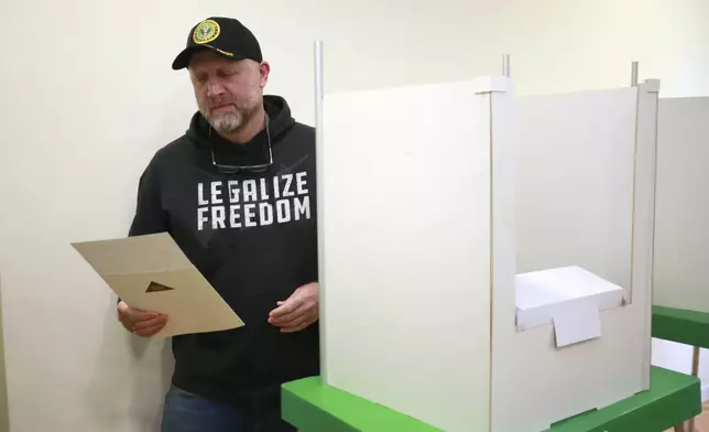 CORRECTS PARTY NAME - Zurab Japaridze, chairman of the Girchi More Freedom party, holds his ballot at a polling station during the parliamentary election in Tbilisi, Georgia, Saturday, Oct. 26, 2024. (AP Photo/Zurab Tsertsvadze)