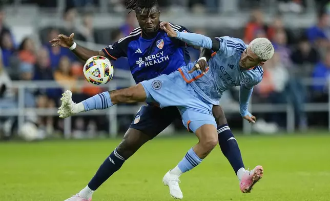 CORRECTS TO MONDAY NOT TUESDAY - FC Cincinnati defender Chidozie Awaziem, left, and New York City FC midfielder Santiago Rodríguez, right, fight for the ball during the first half of a first-round soccer match of the MLS Cup playoffs, Monday, Oct. 28, 2024, in Cincinnati. (AP Photo/Carolyn Kaster)