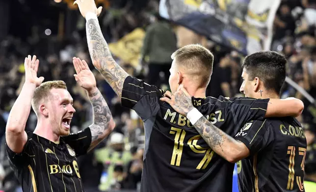 CORRECTS TO SECOND HALF FROM FIRST HALF - Los Angeles FC midfielder Lewis O'Brien, left, celebrates a goal by forward Cristian Olivera, right, with midfielder Mateusz Bogusz (19) against the Vancouver Whitecaps during the second half of the first match of an MLS Cup playoffs opening round in Los Angeles, Sunday, Oct. 27, 2024. (AP Photo/Alex Gallardo)